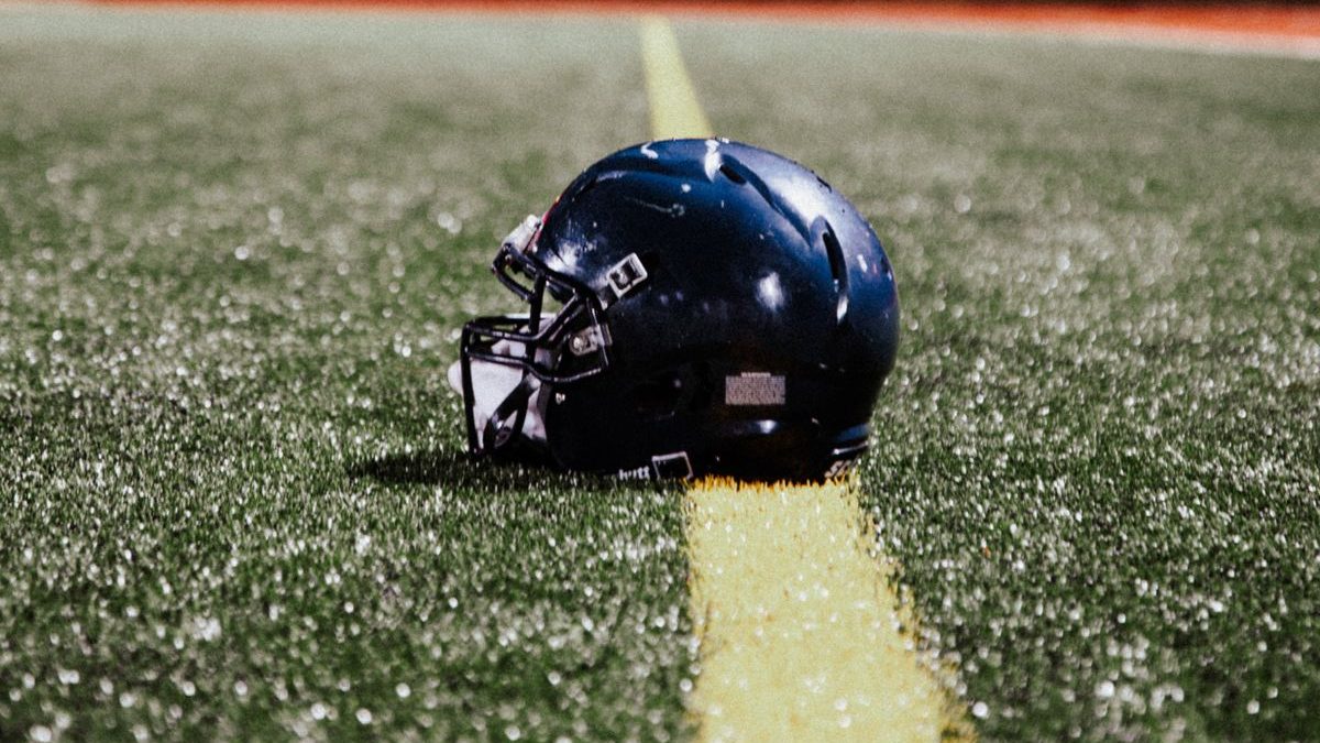 A football helmet resting on the wet turf under night lights.